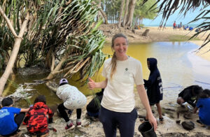 Julie Zill leads a group of people planting plants along a stream in Hawaii