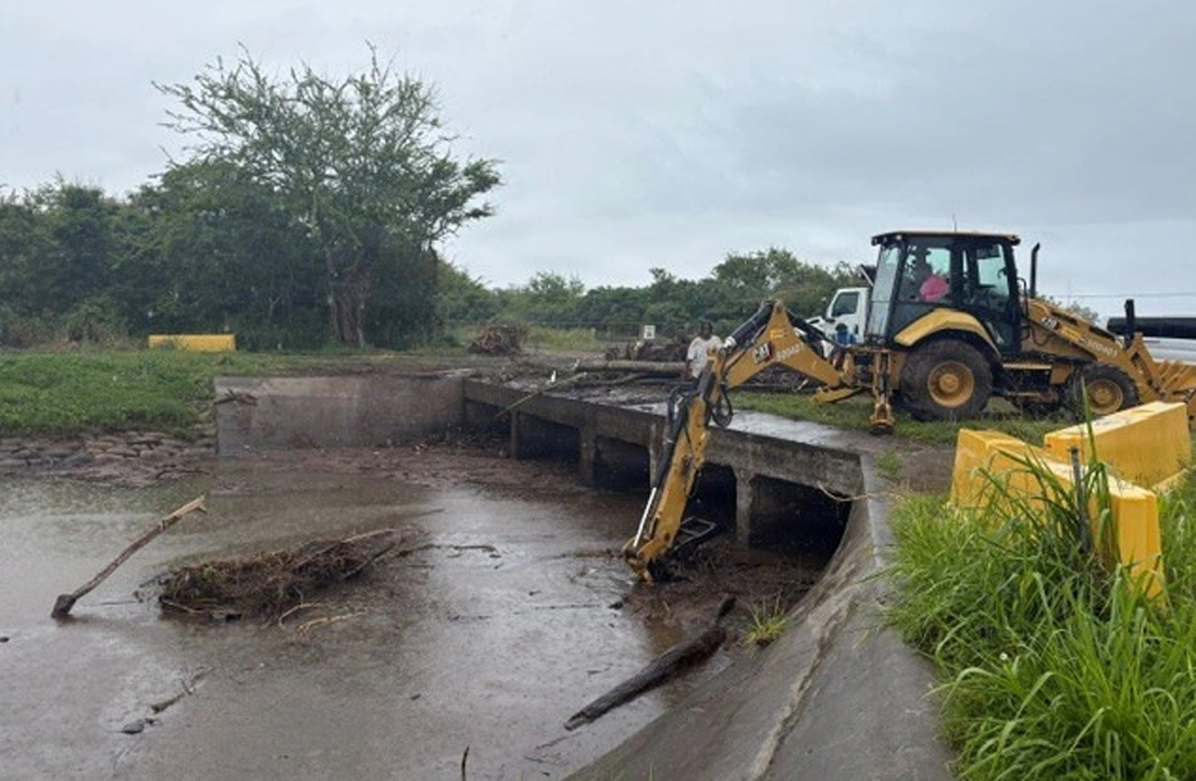 heavy equipment moves storm debris preventing water from moving under a bridge in Hawai'i