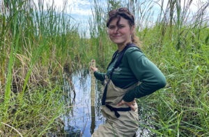 a woman stands up to her waist in a marsh in Florida