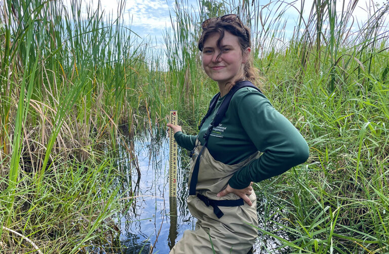 a woman stands up to her waist in a marsh in Florida